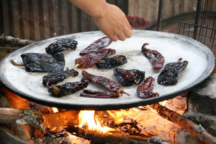 Dried chiles roasting on a comal over open fire